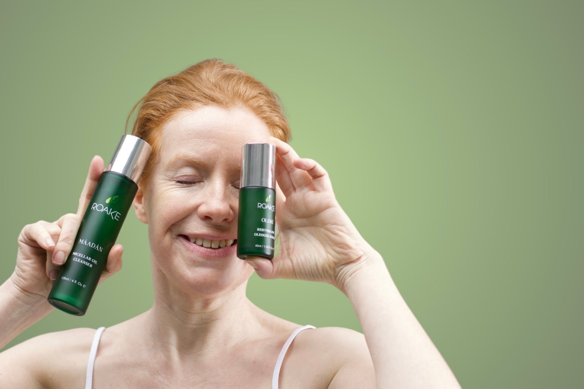 Woman holding Máadán Micellar Oil Cleanser and Olorì Rejuveglow Oleogel Serum.