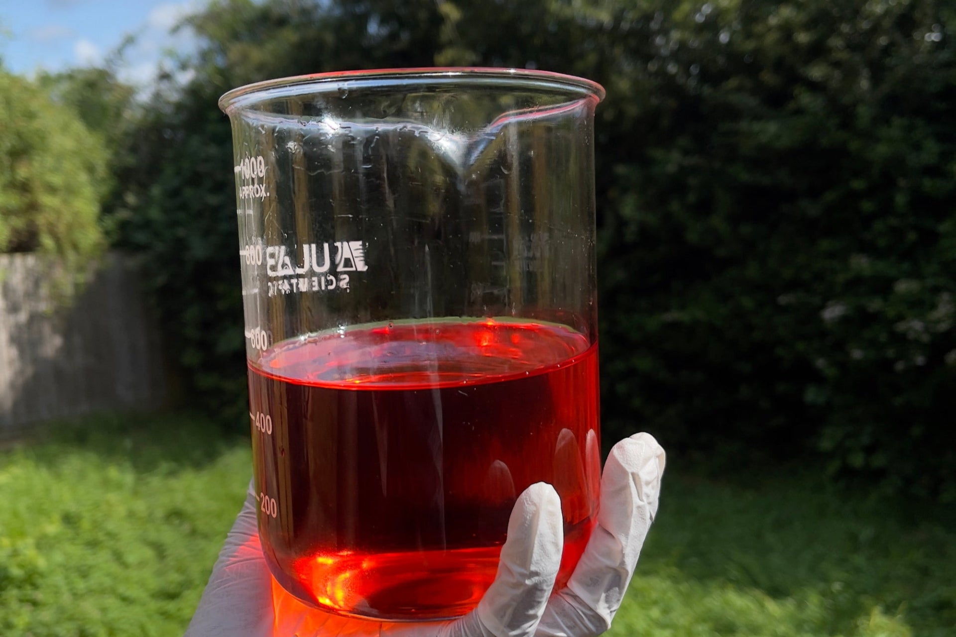 Roake founder holding a beaker of rosehip oil, a nourishing, antioxidant-rich oil for hydration and skin renewal.